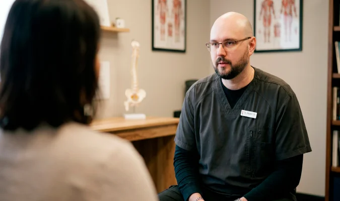 Chiropractor listening to a patient after a car accident at Northwest Hinojosa Chiropractic